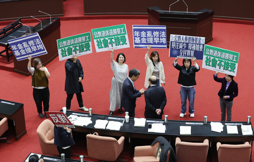立法院會12日院會三讀通過「公務人員退休資遣撫卹法部分條文修正草案」,民進黨立委手持標語表達不滿,並高喊「年金亂修法,基金提早垮」。(姚志平攝)