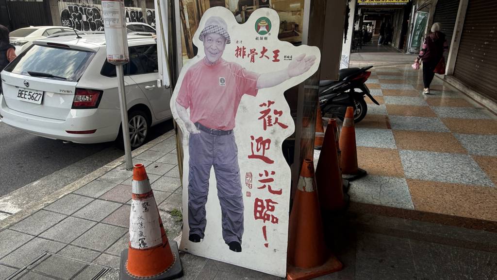 多年來始終不變的「老闆在門口歡迎你」人形立牌。(施景耀 攝)